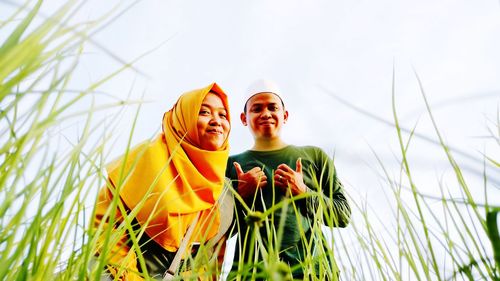 Young woman smiling on field against sky