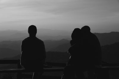 Rear view of silhouette man standing on mountain against sky