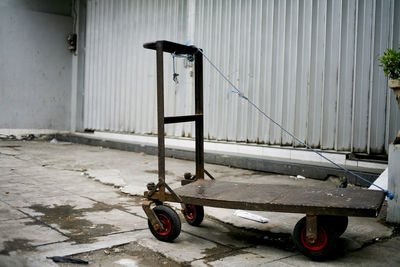Abandoned cart on street against wall