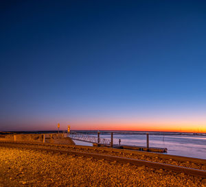 Scenic view of beach against clear sky at sunset