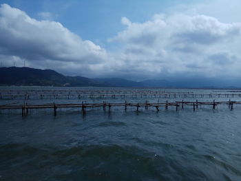 Wooden posts in sea against sky