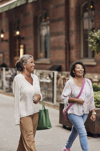 Smiling woman walking with female disabled friend at street