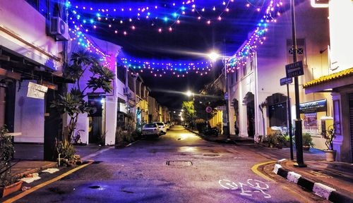 Illuminated street amidst buildings at night