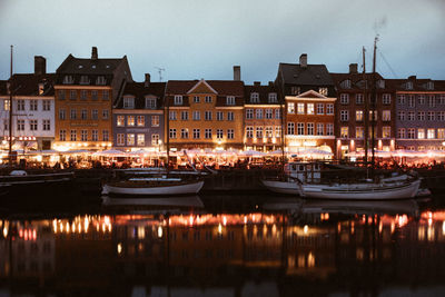 Boats moored in canal against buildings at night