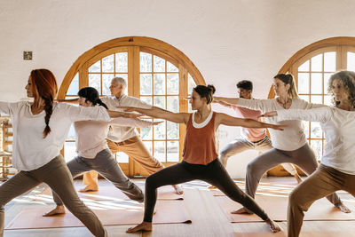 Yoga instructor teaching warrior position to students in class