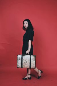 Portrait of young woman standing against red background