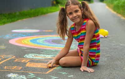 Portrait of girl drawing on road with chalk