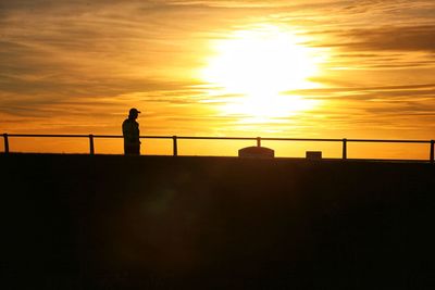 Low angle view of silhouette man standing on pier against sky during sunset