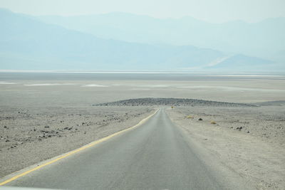 Road leading towards mountains against sky