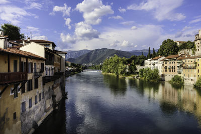 Houses by brenta river against sky in bassano del grappa, italy.