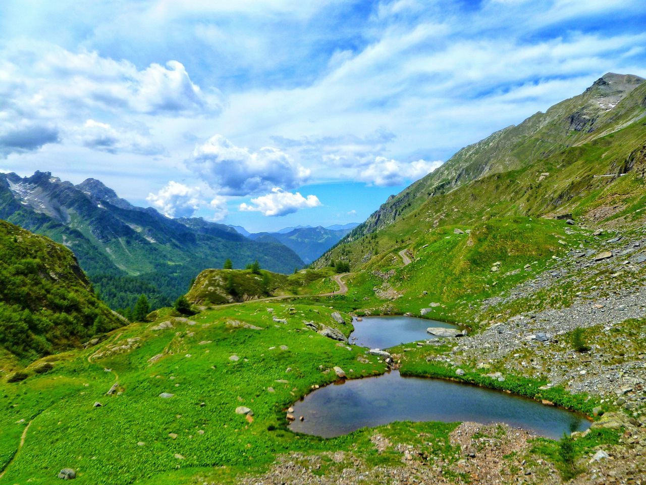 tranquil scene, water, mountain, tranquility, scenics, cloud - sky, beauty in nature, landscape, stream, non-urban scene, sky, grass, nature, green color, calm, reflection, mountain range, solitude, day, majestic, canal, narrow, green, remote, flowing, countryside, outdoors, lakeside, tourism