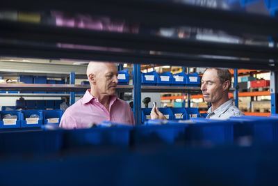 Two men in storehouse examining screw