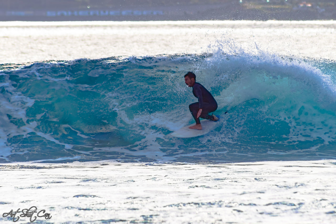 MAN SURFING ON SEA SHORE