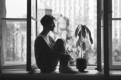 Rear view of woman looking through window