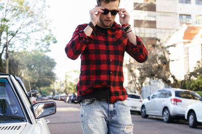 Man wearing plaid shirt and sunglasses while standing on road