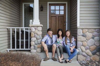 Portrait of happy family sitting at entrance