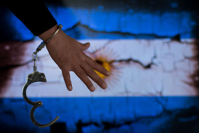 Cropped hand of male criminal with handcuffs against argentinian flag