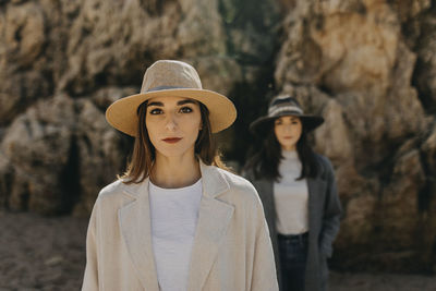 Beautiful female twins against rock formation at beach