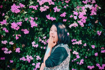 Portrait of woman standing by pink flowering plants