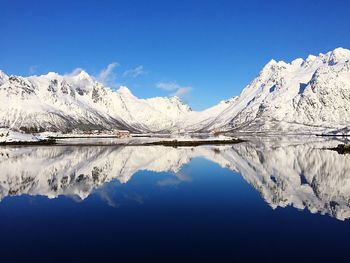 Scenic view of lake and mountains against blue sky