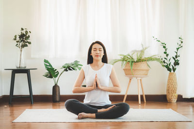 Full length of woman sitting on potted plant