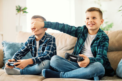 Playful siblings playing video game at home