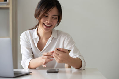 Happy asian woman using her credit card for online shopping at home office.