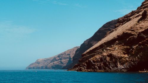 Scenic view of sea by cliff against sky