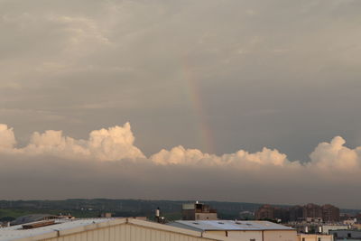 Rainbow over buildings in city against sky