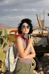 Young woman wearing sunglasses standing against sky