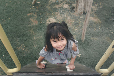 High angle view portrait of cute girl playing on outdoor play equipment at park