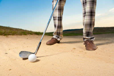 Low section of man playing golf on sand