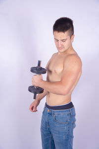 Full length of shirtless man standing against white background