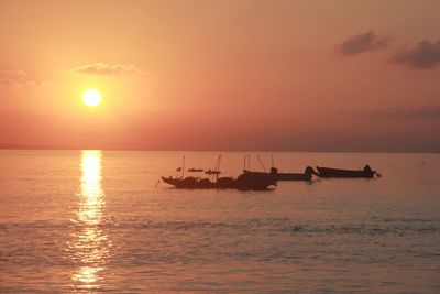 Silhouette boat in sea against sky during sunset