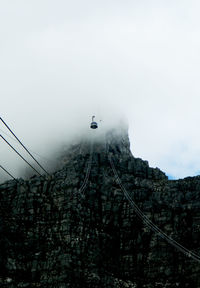 Low angle view of overhead cable car against sky