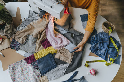 Hands of fashion designer sewing clothes on machine at table