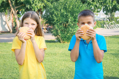 Schoolchildren eat hamburgers in the park. lunch after school.