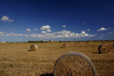 Hay bales on agricultural landscape against sky