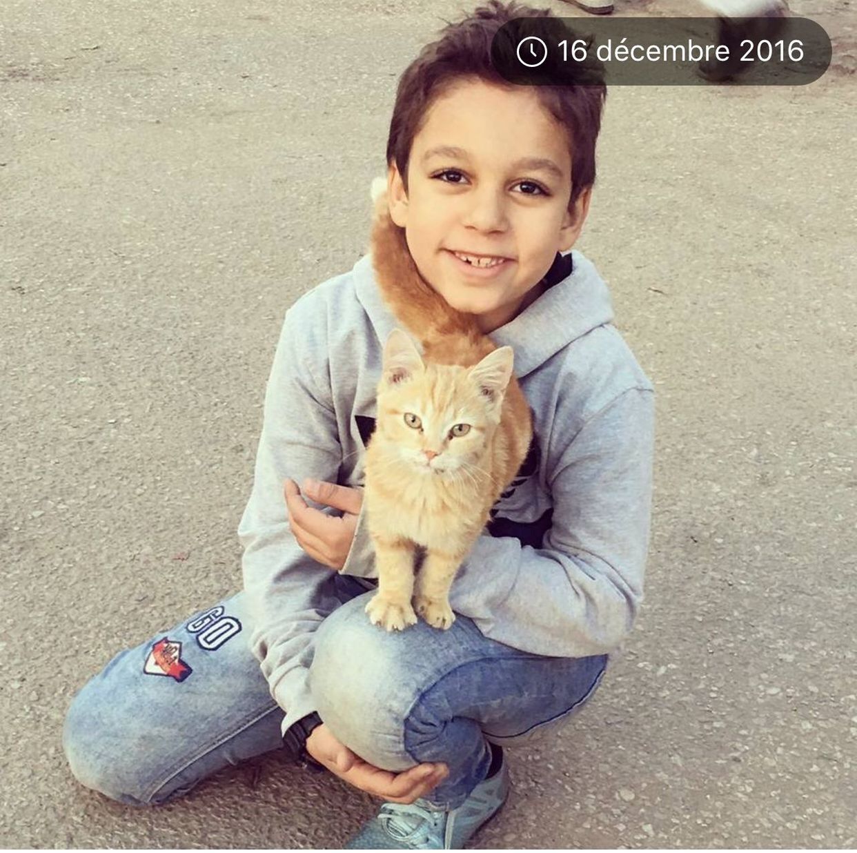 looking at camera, portrait, pets, one person, one animal, smiling, childhood, sitting, domestic animals, cute, dog, animal themes, holding, child, day, people, happiness, real people, outdoors, friendship, full length, children only, mammal, one boy only, adult