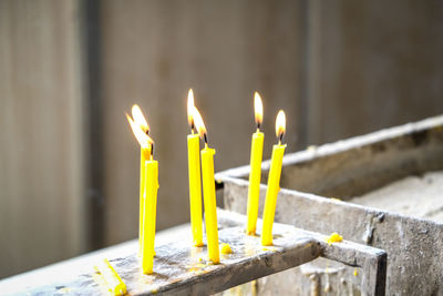 Close-up of yellow candles on temple against building