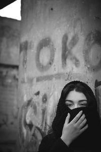 Portrait of a young woman standing against wall