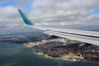 Airplane flying over sea against cloudy sky