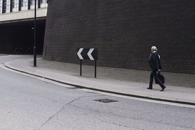 Senior businessman with luggage walking on pavement