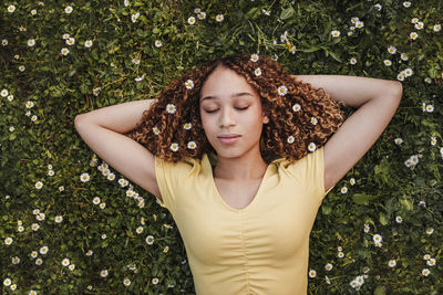 Beautiful young woman lying down against plants