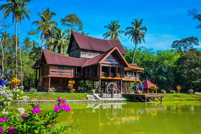 House by lake and trees against sky