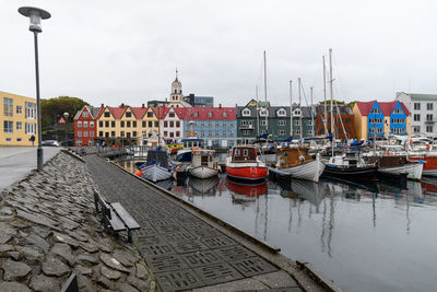 Boats moored at harbor by buildings in city