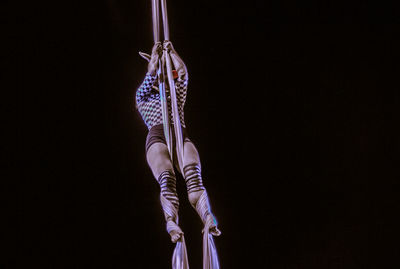 Woman hanging against black background