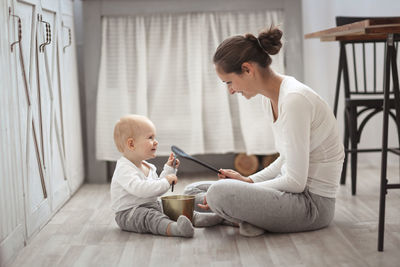 Mother plays with her son baby on the floor in a real bright interior, the concept of motherhood 