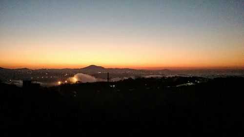 Silhouette cityscape against clear sky during sunset