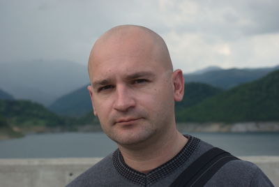 Close-up portrait of bald man against mountain